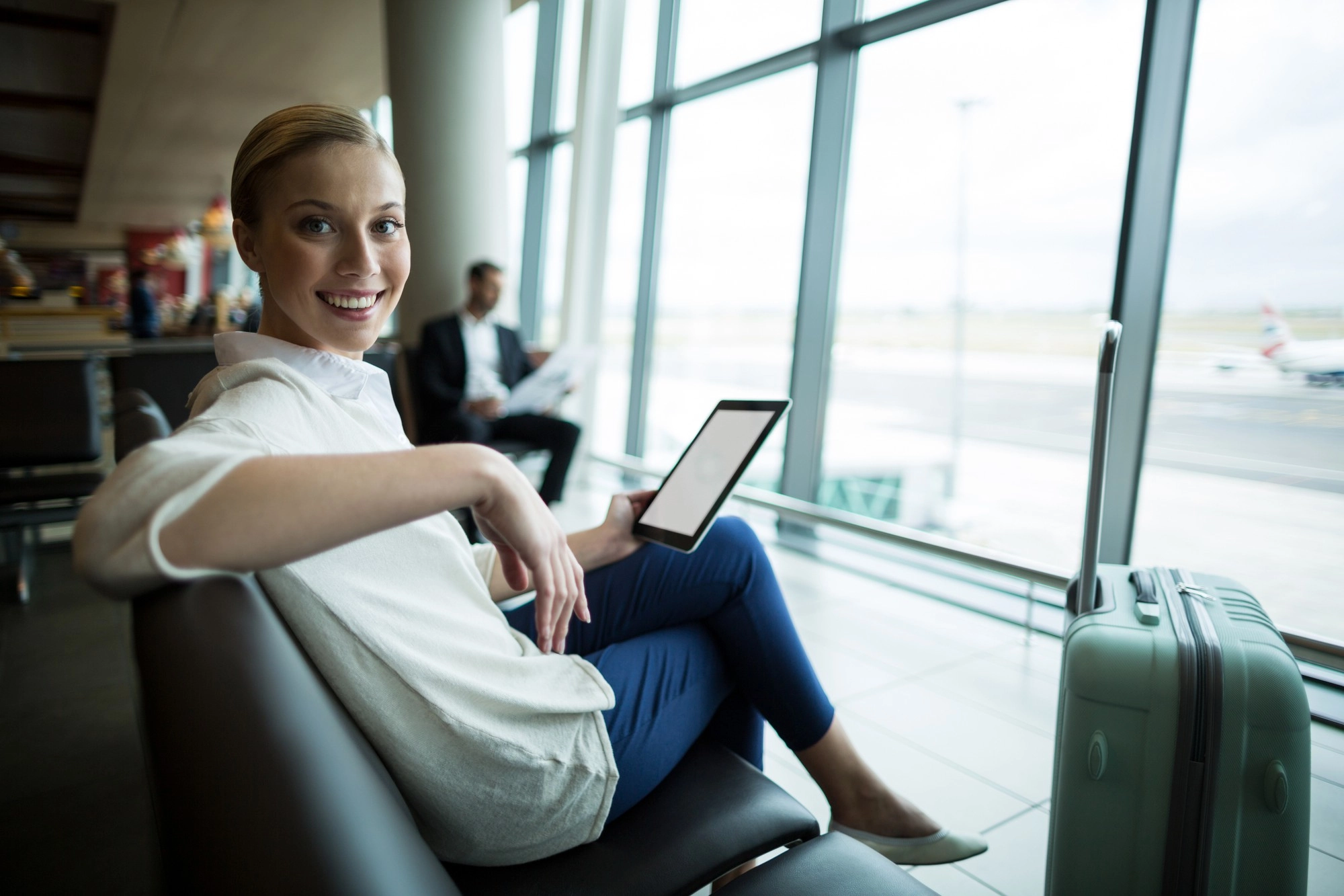 Viaggiatore in attesa all’Aeroporto Marco Polo di Venezia con tablet e bagaglio, vicino al Titian Inn Hotel Venice Airport